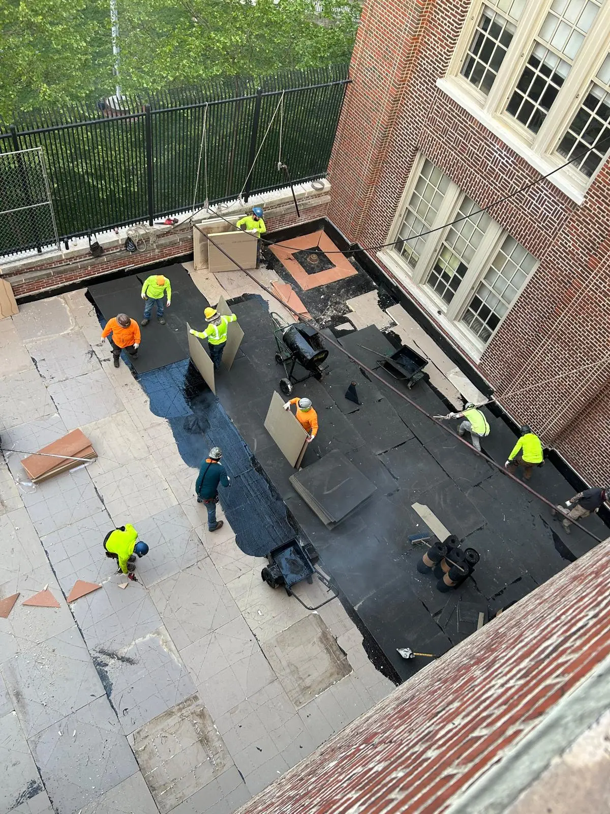 Construction team applying waterproofing membrane on a rooftop deck as part of NYC commercial project